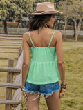 Woman wearing green Openwork Cami with scoop neck and ruched design, standing in a park wearing denim shorts and a hat, back view.