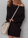 Woman wearing black asymmetric batwing sweater dress with a white handbag.