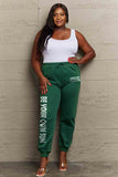 Woman wearing Graphic Sweatpants with 'BE YOUR OWN SUN' print, showcasing adjustable drawstring waistband and relaxed fit.
