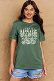 Woman wearing a green Graphic Cotton T-Shirt with 'CREATE HAPPINESS' slogan in floral print, paired with denim shorts.