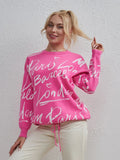Letter Pattern Sweater with drawstring hem and dropped shoulders in pink worn by a woman standing against a white textured wall.