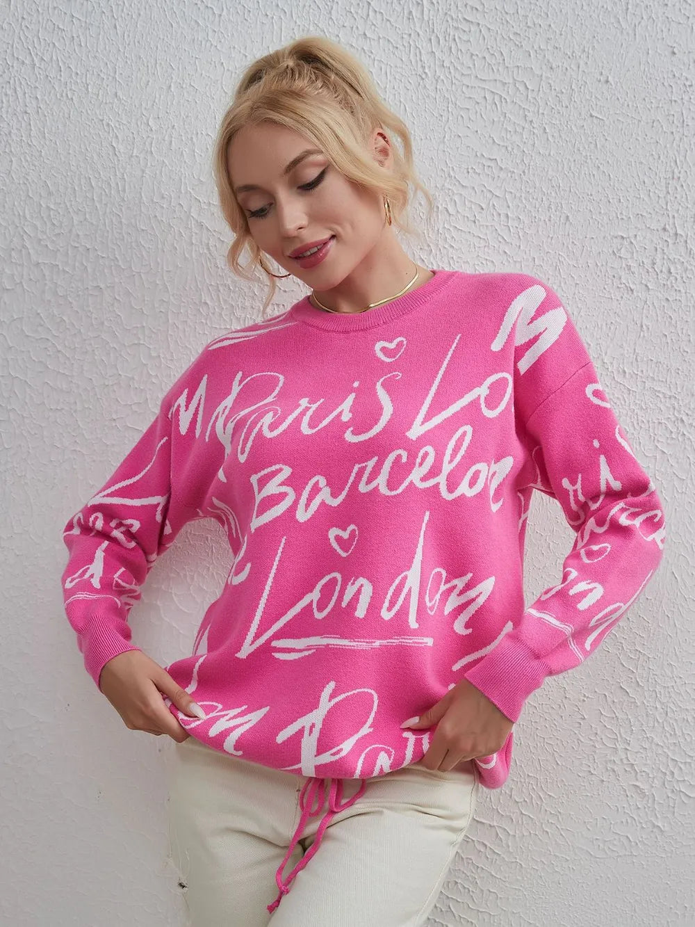 Woman wearing pink Letter Pattern Sweater with drawstring hem and dropped shoulder.
