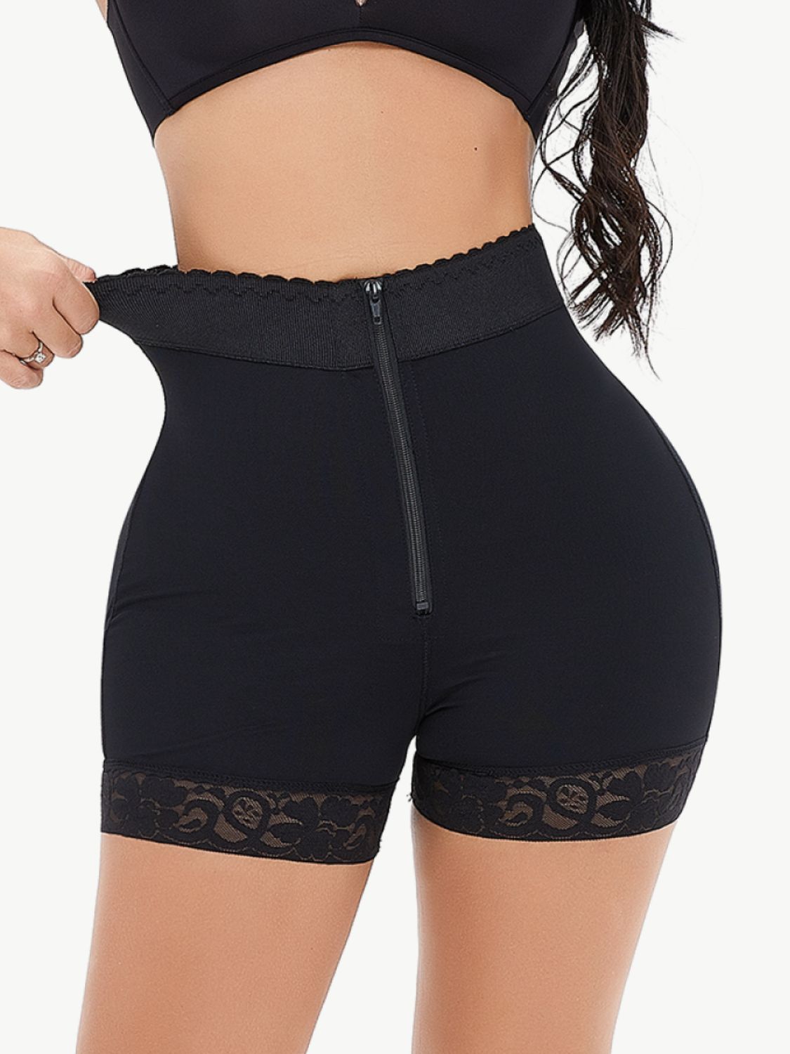 Woman wearing black full size zip-up lace trim shaping shorts in a studio setting