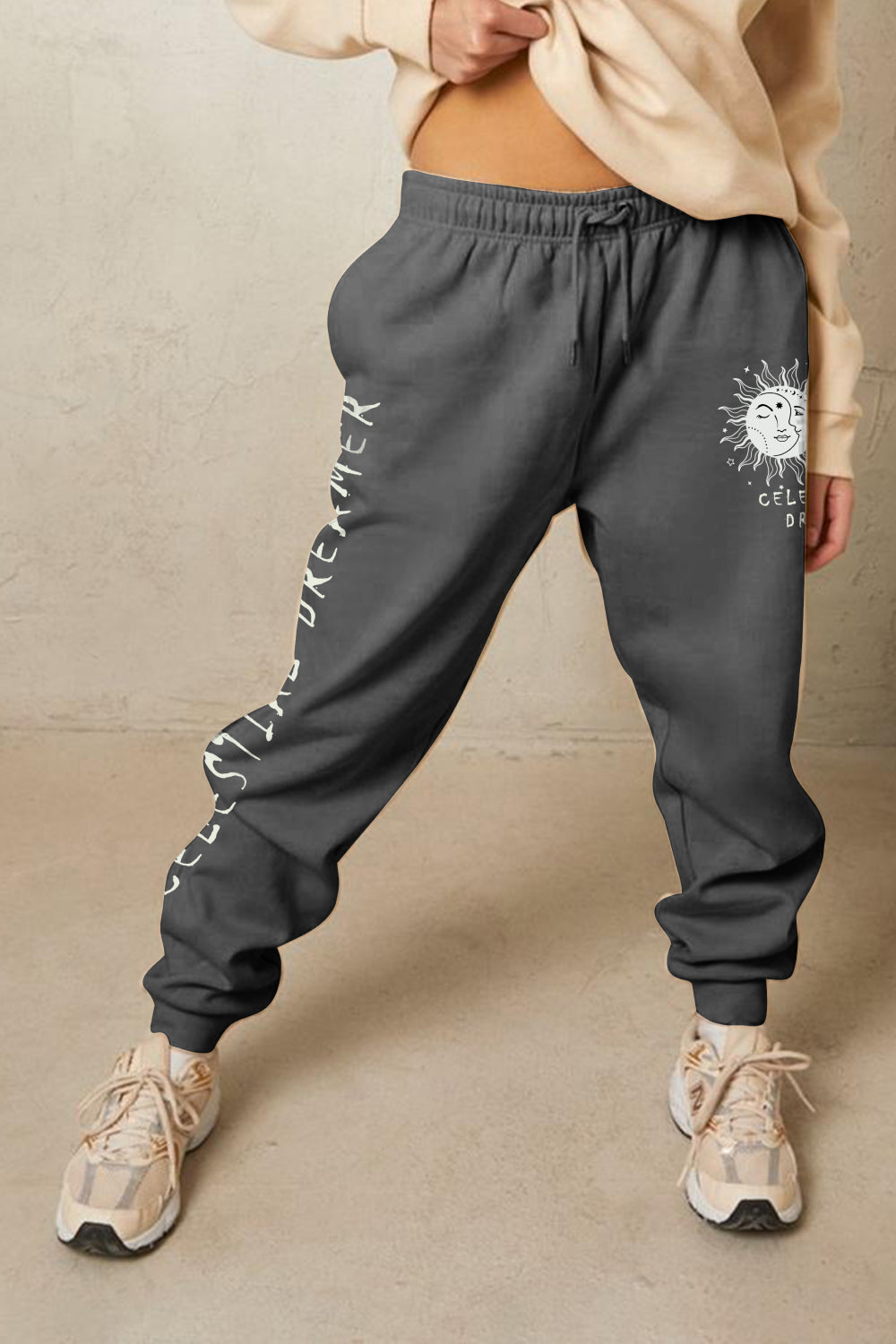 Person wearing Graphic Sweatpants with 'CELESTIAL DREAMER' print, soft cotton-poly blend, ideal for casual, comfortable style.