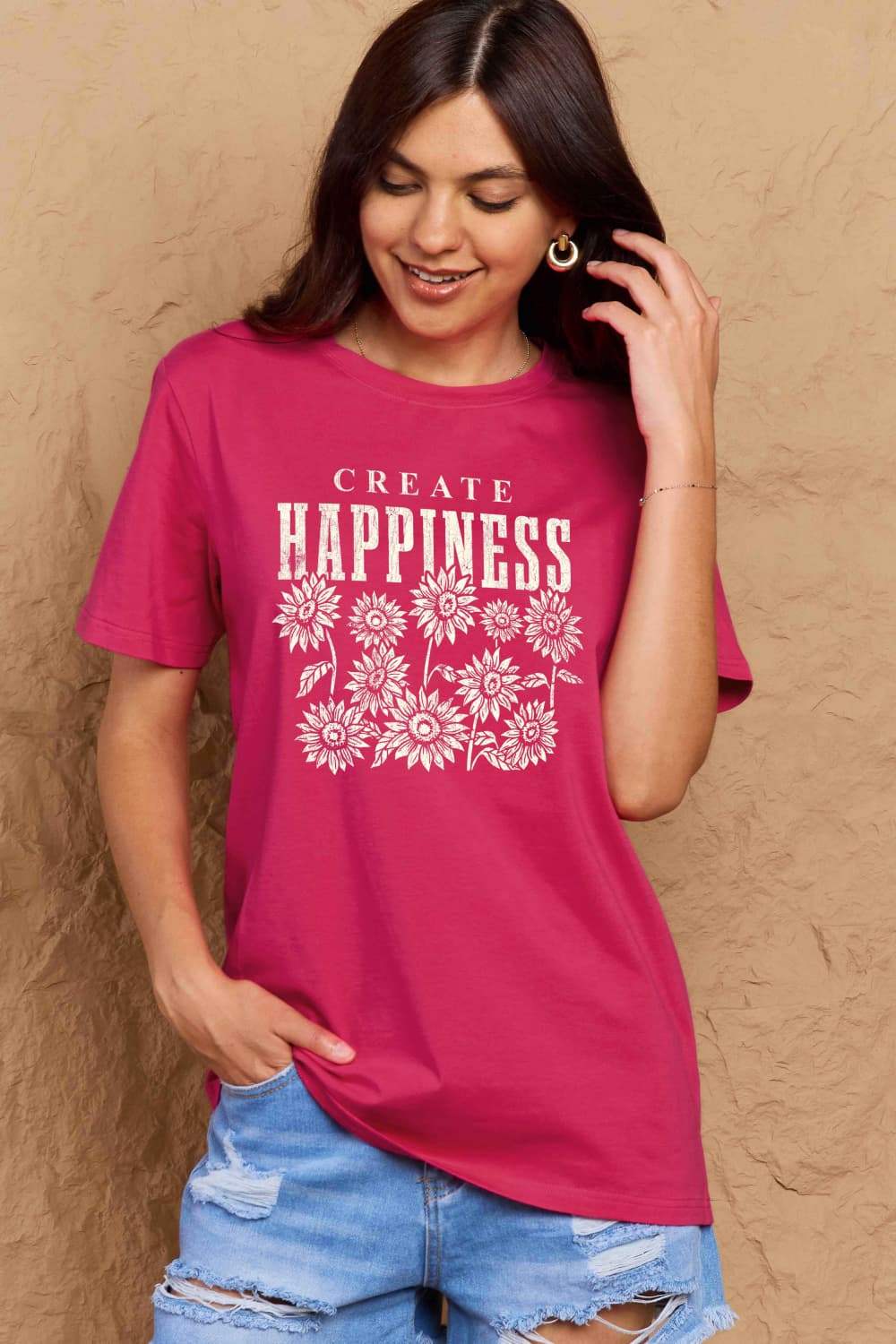 Woman wearing a Graphic Cotton T-Shirt with CREATE HAPPINESS slogan, perfect for casual wear and positive vibes.