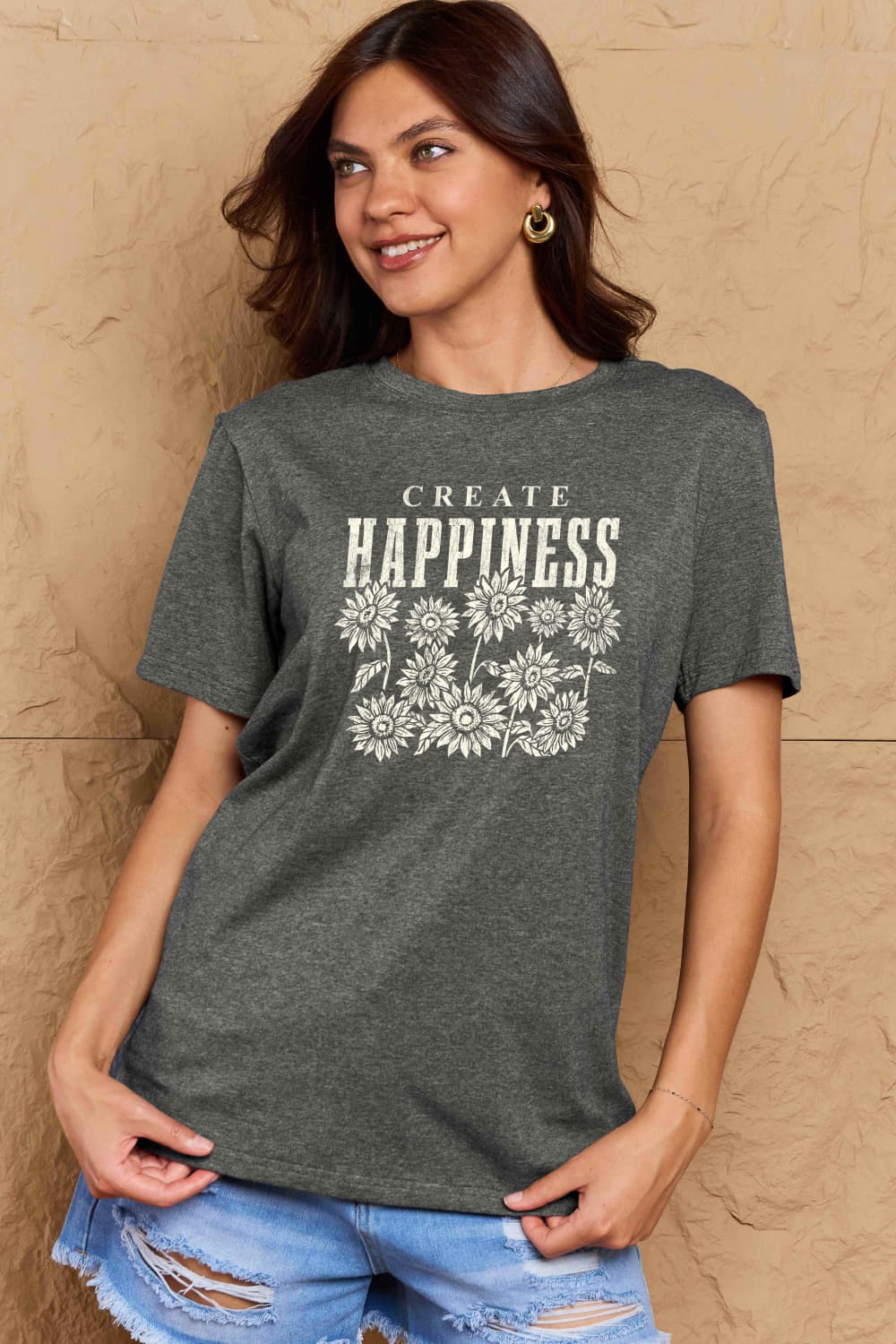 Woman wearing Graphic Cotton T-Shirt with 'CREATE HAPPINESS' slogan, dark gray, casual style, promoting a positive vibe and comfort.