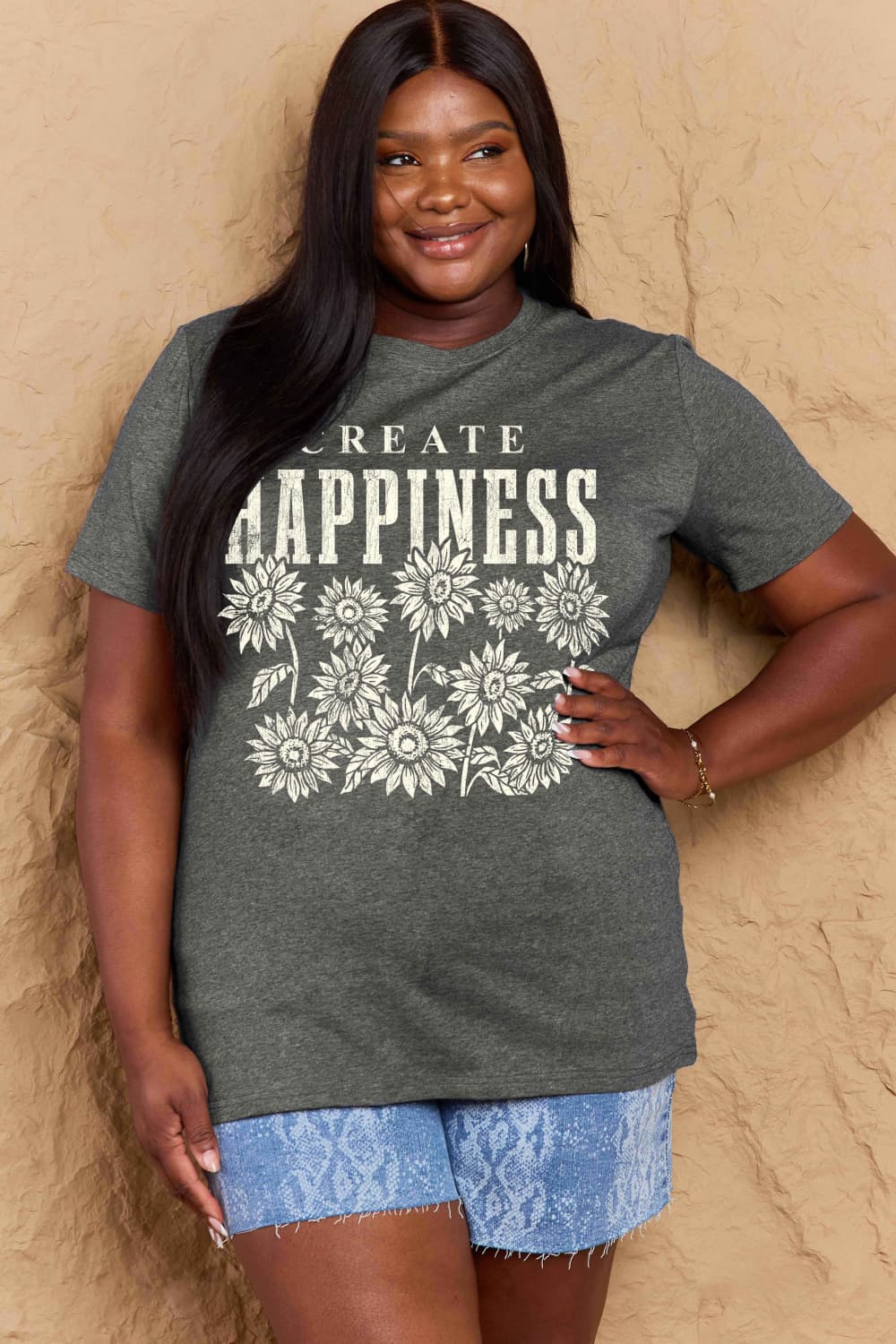 Woman wearing Graphic Cotton T-Shirt with 'CREATE HAPPINESS' slogan, styled with denim shorts, showcasing casual and uplifting fashion.