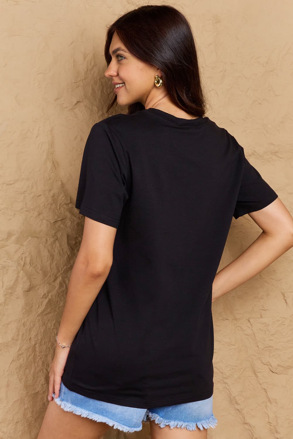 Back view of woman wearing Graphic Cotton T-Shirt with GRATEFUL Flower Print, showcasing the casual fit of the shirt.