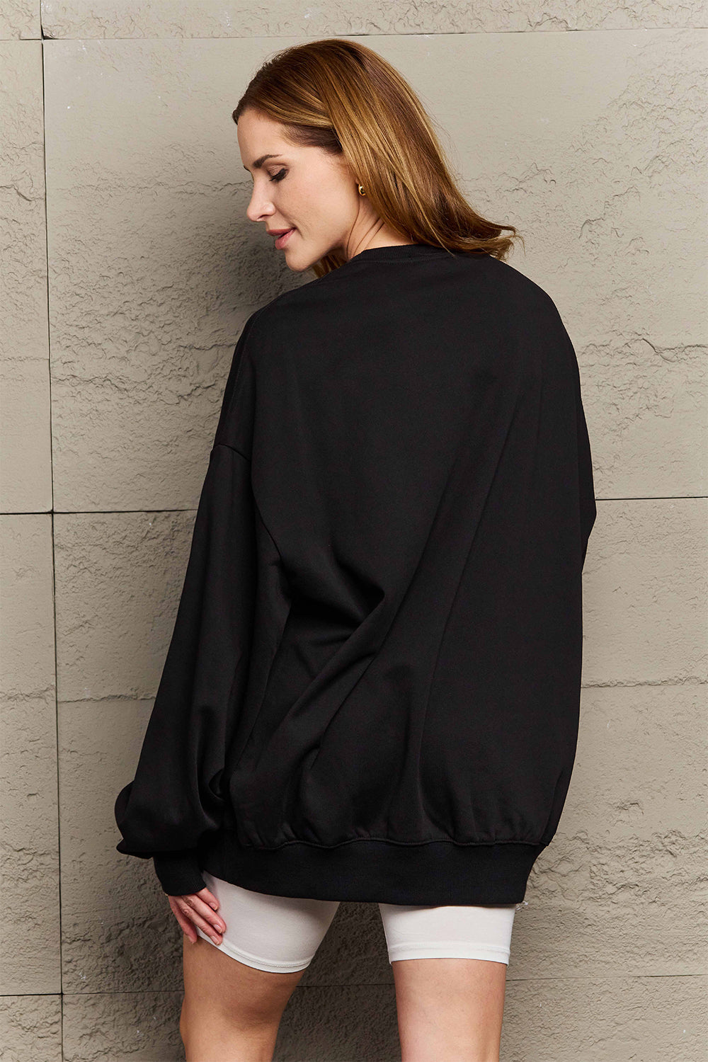 Woman wearing Graphic Dropped Shoulder Sweatshirt in black, showcasing casual and relaxed style for everyday wear.