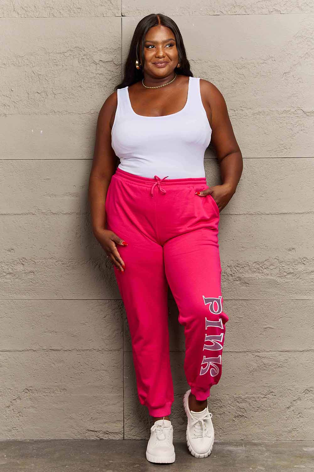 Woman wearing Graphic Sweatpants with PINK print, featuring drawstring waistband, ideal for casual wear and style.