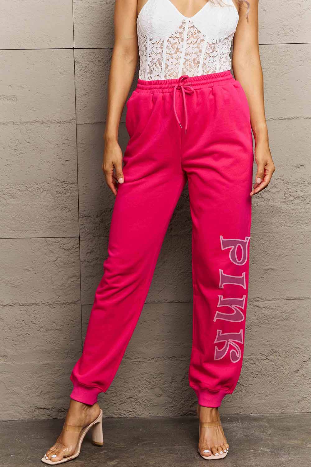 Woman wearing Graphic Sweatpants with PINK print, showcasing drawstring waistband and relaxed fit, ideal for style and comfort.