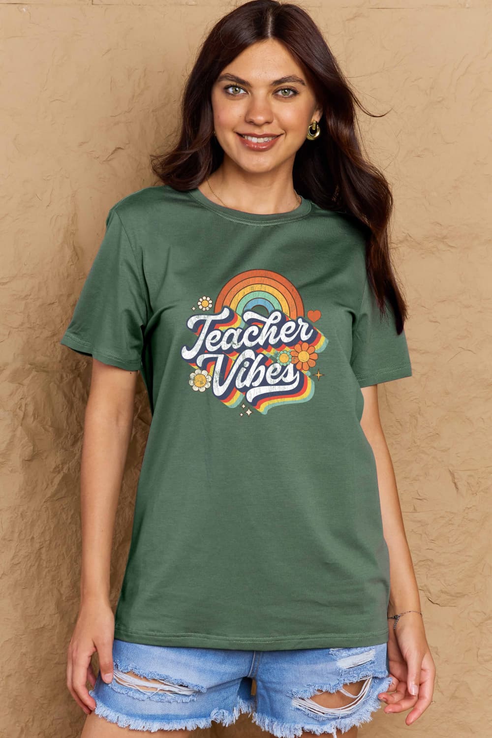 Graphic Cotton T-Shirt with TEACHER VIBES print on a model, featuring a colorful slogan on a green t-shirt, perfect for casual wear.